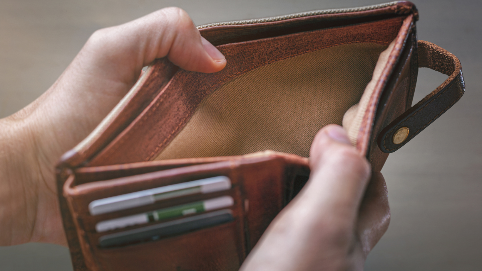 Hands opening a wallet but no money is inside.